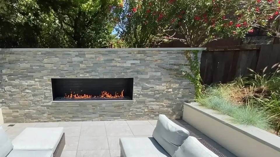 Outdoor lounge with a gas fireplace in a stone veneer wall