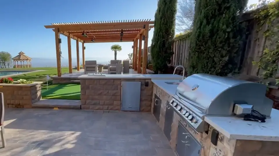 Outdoor kitchen with built-in grill under a wood pergola
