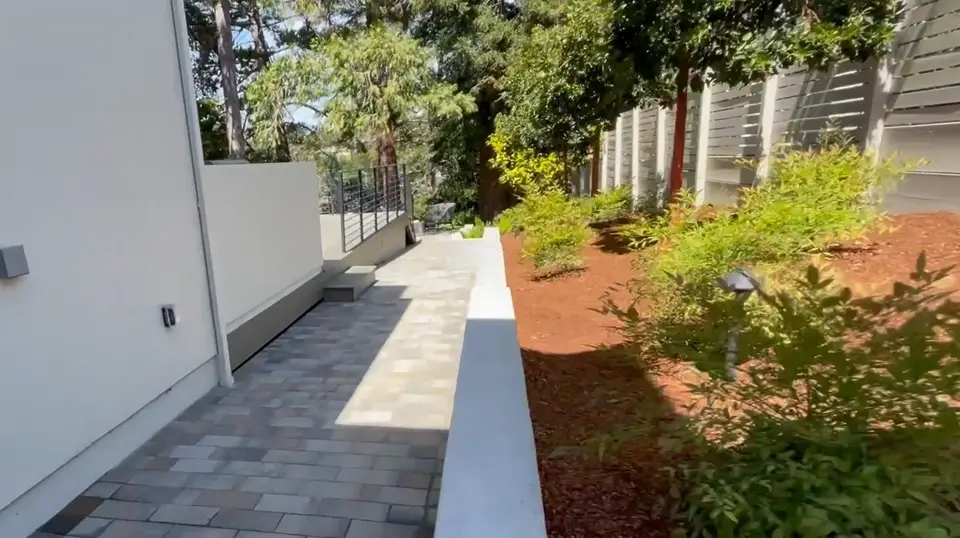 Paver side walkway with a low concrete retaining wall and new plantings