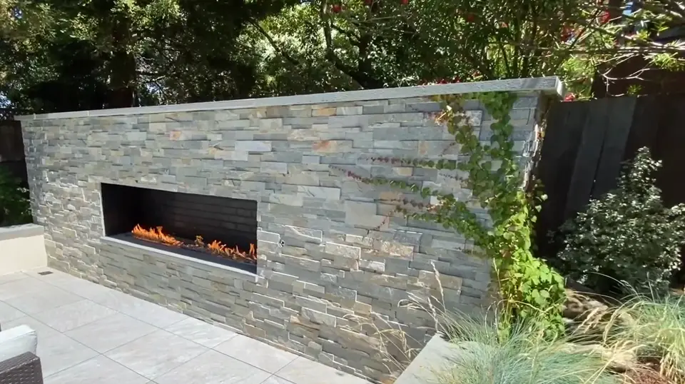 Porcelain patio with a stacked stone veneer linear fireplace
